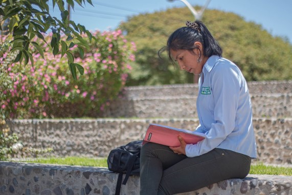 Estudiante universitaria leyendo un libro al aire libre