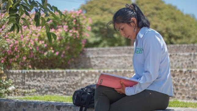 Estudiante universitaria leyendo un libro al aire libre