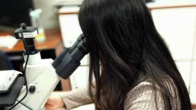 Joven revisando un telescopio en un laboratorio.