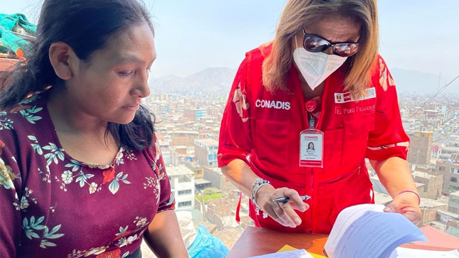 Fotografía de la madre firmando unos documentos que le muestra la coordinadora del conadis