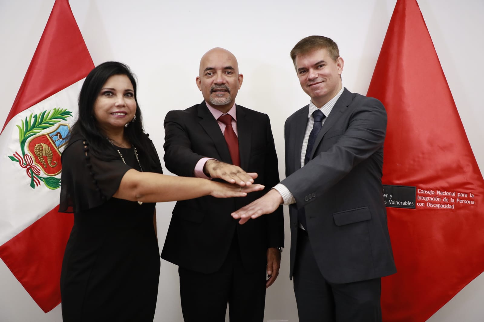 Fotografía del presidente del conadis, representante de Amdocs Perú y Fundación Telefónica juntando las palmas de las manos