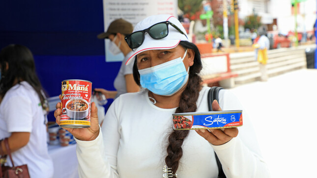 Imagen de una mujer sujetando latas de conserva de pescado