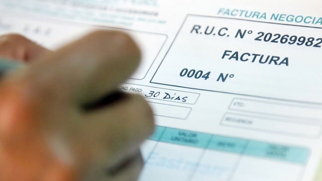Imagen de una mano escribiendo sobre una factura