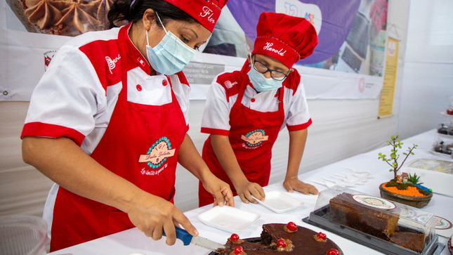 Madre e hijo cortado una tota de chocolate sobre una mesa  que tiene varios adornos.  