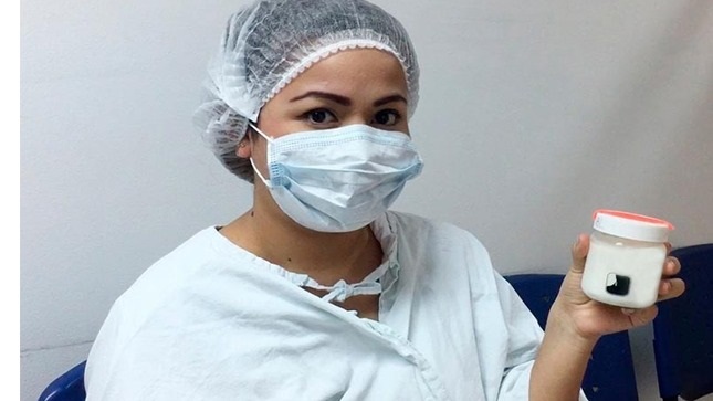 En la foto se ve a una mujer mostrando su leche que ha dejado para el Banco.