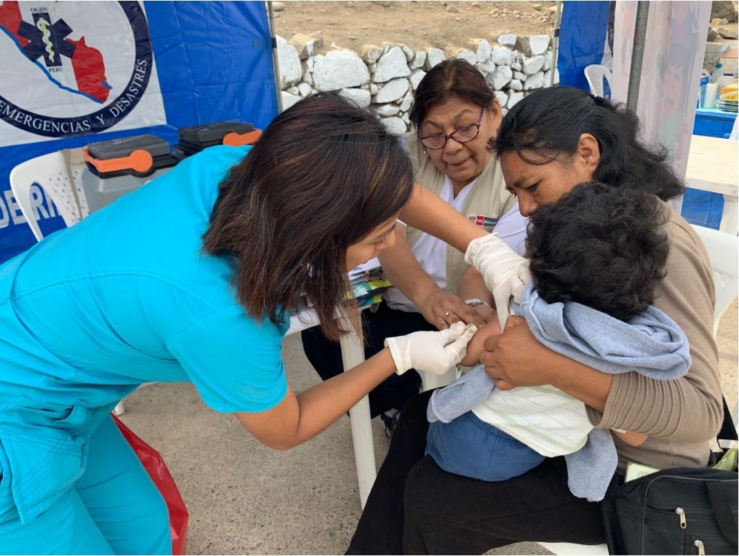 En la foto una enfermera está vacunando a una niña.