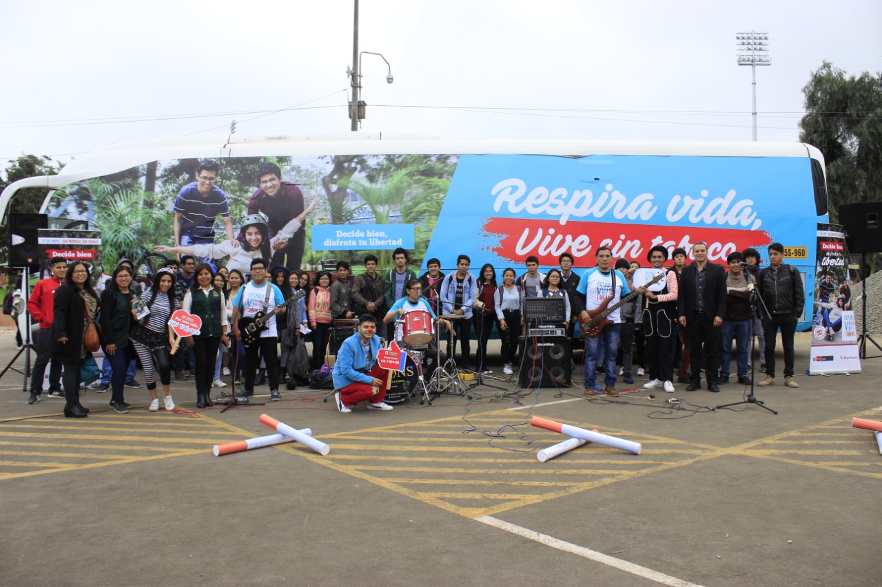 Se observa un grupo de jóvenes delante del bus antitabaco.