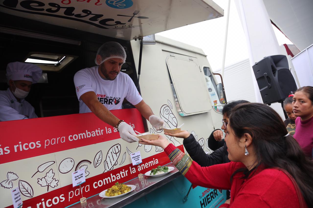 En la foto se ve unas mujeres recibiendo comida rica en hierro del bus Food Truck.