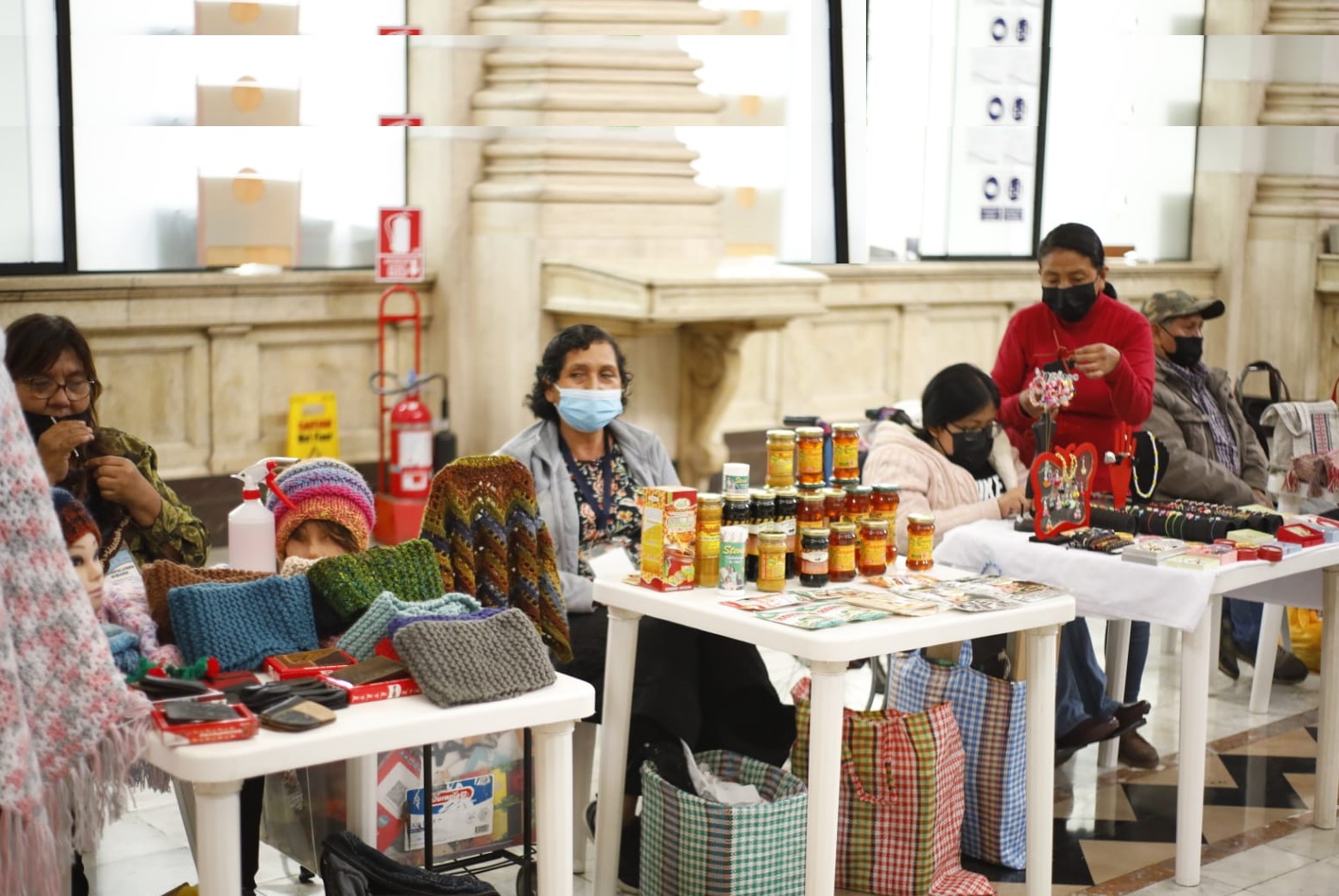 Personas con discapacidad exponiendo su productos sobre una mesa y personas comprando , en la sede del Congreso de la República en sus instalaciones del edificio Luis Alberto Sánchez, en el Cercado de Lima.