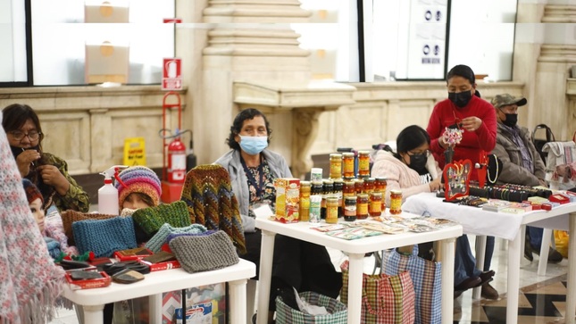 Personas con discapacidad exponiendo su productos sobre una mesa  y personas comprando , en la sede del Congreso de la República en sus instalaciones del edificio Luis Alberto Sánchez, en el Cercado de Lima.