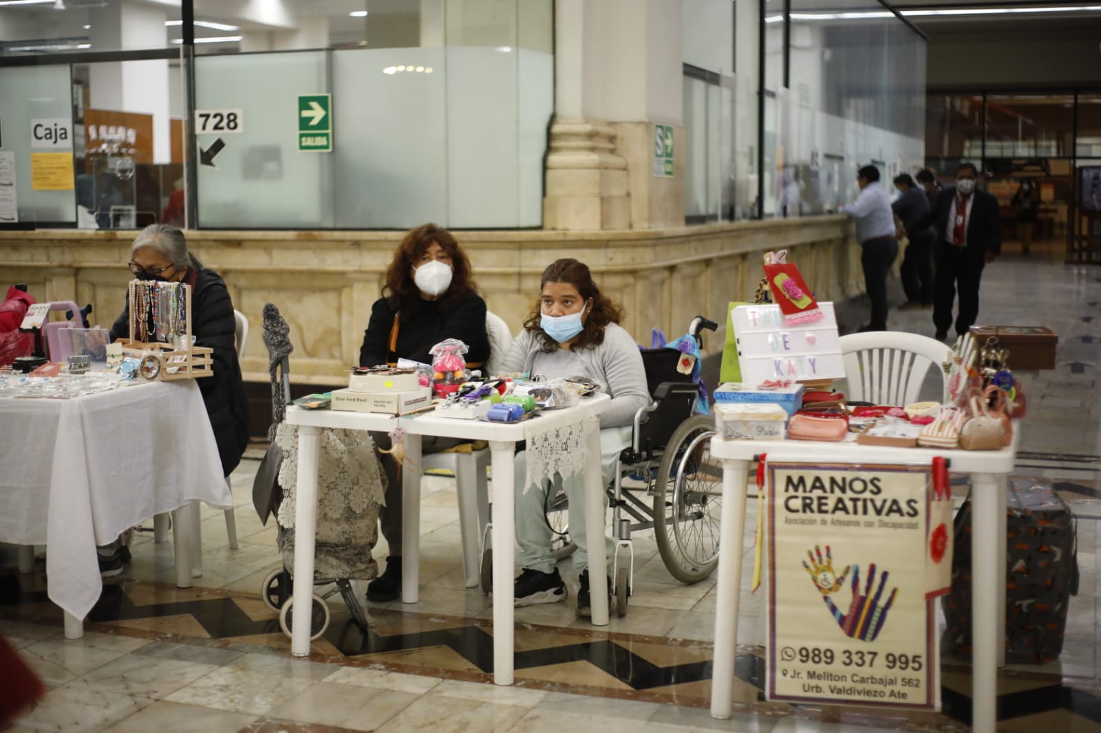 Personas con discapacidad de varias organizaciones exponiendo su productos sobre una mesa y personas comprando , en la sede del Congreso de la República en sus instalaciones del edificio Luis Alberto Sánchez, en el Cercado de Lima.