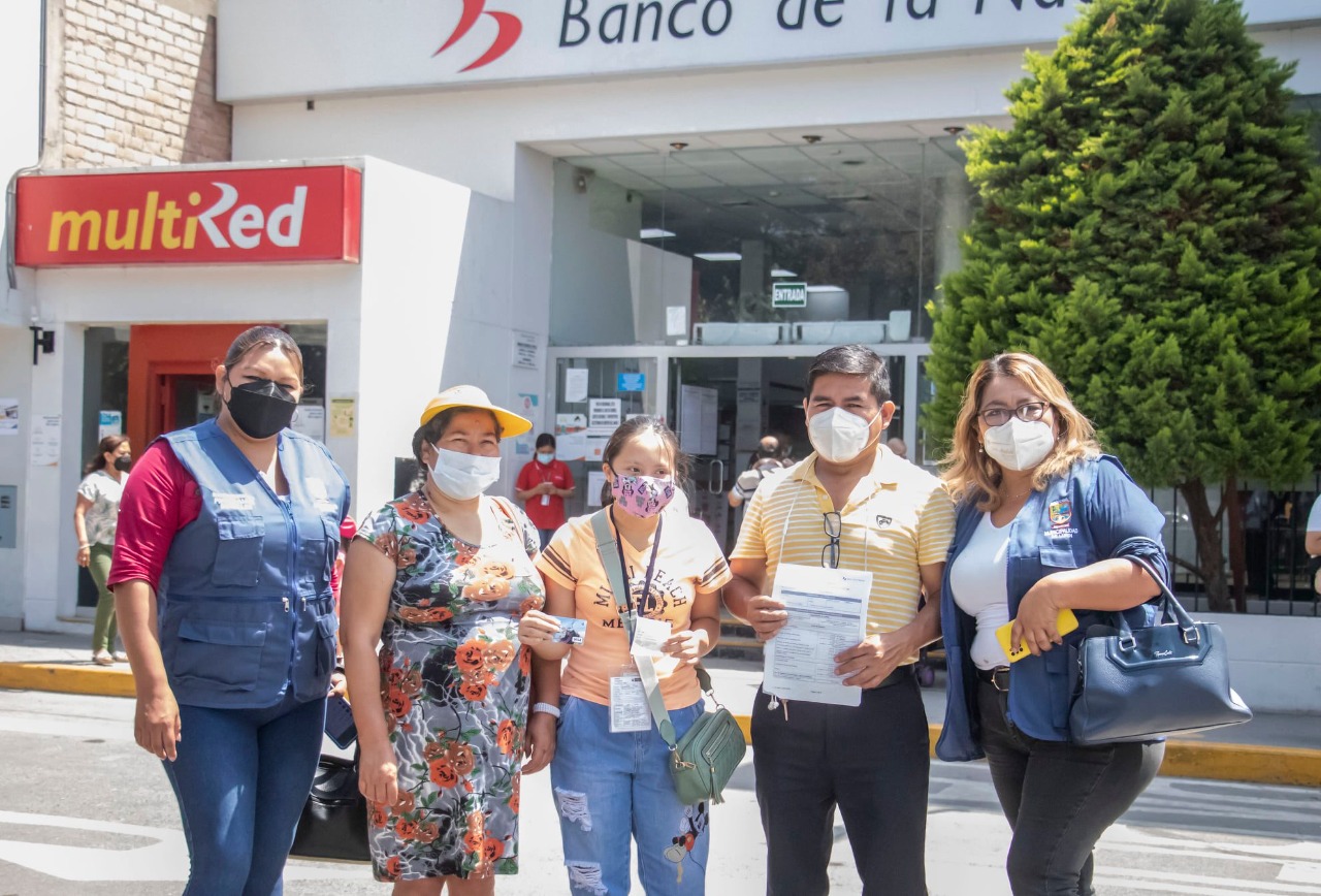 Usuaria del programa CONTIGO y familia al frente de un banco de la nación 