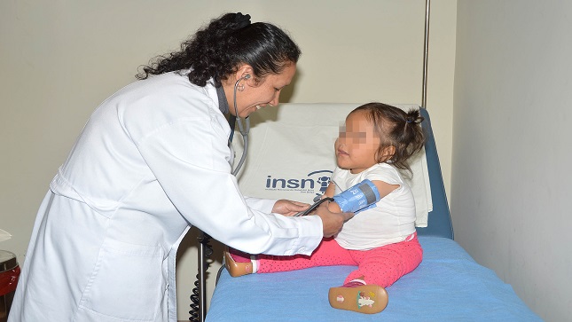 En la foto una niña esta acompañada de su madre, mientras es atendida por el médico.