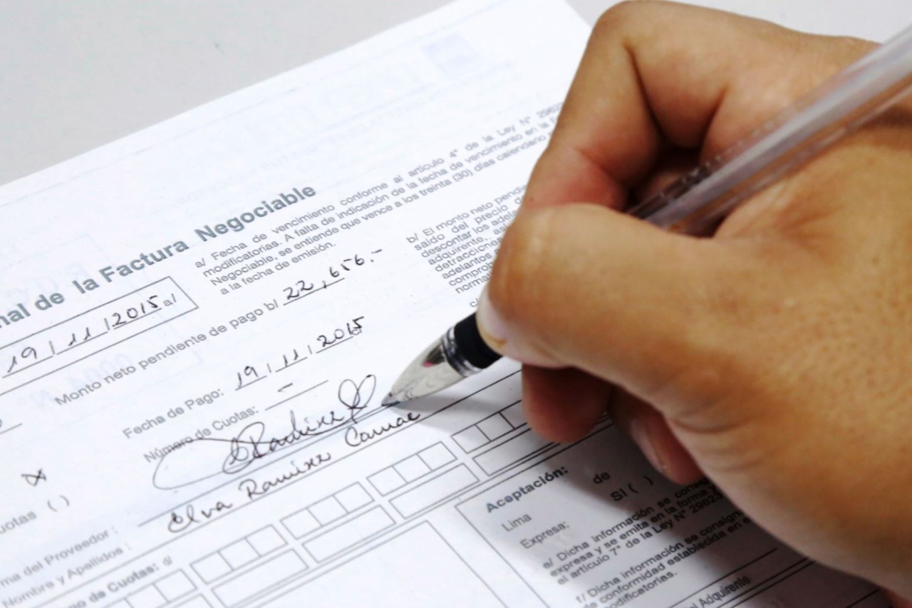 Imagen de persona firmando una factura negociable