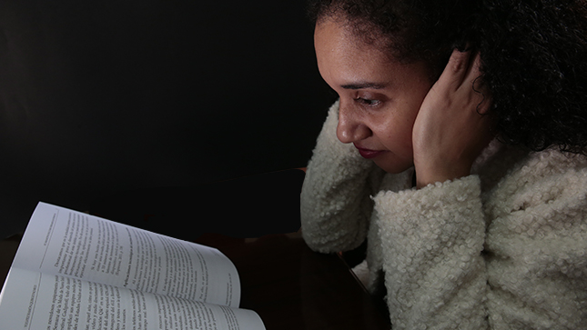 En la foto aparece una mujer frente a un libro, con expresión de no entender lo que lee.