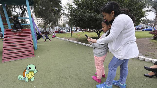 En la foto aparece una niño con un celular en la mano y junto a su madre.