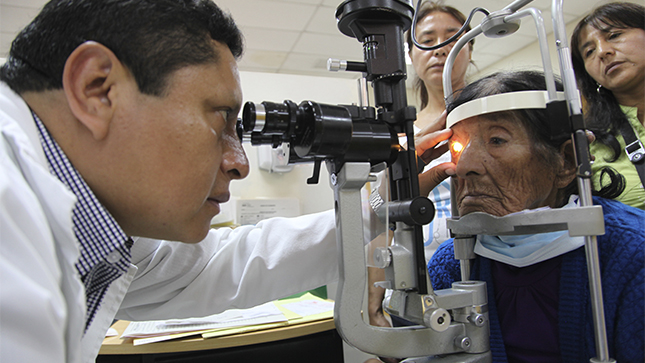 En la foto un médico oftalmólogo realiza un chequeo médico a una mujer mayor de edad.