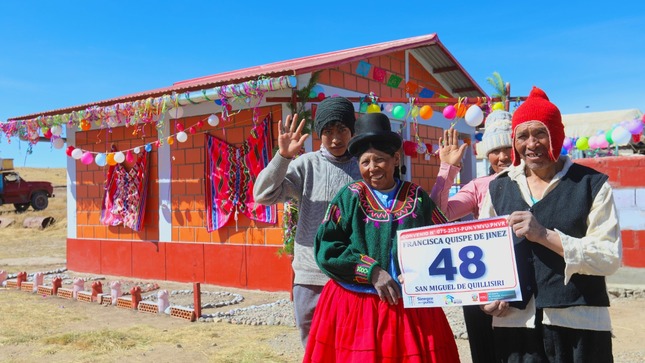 Familia saludando en el frontis de su casa.