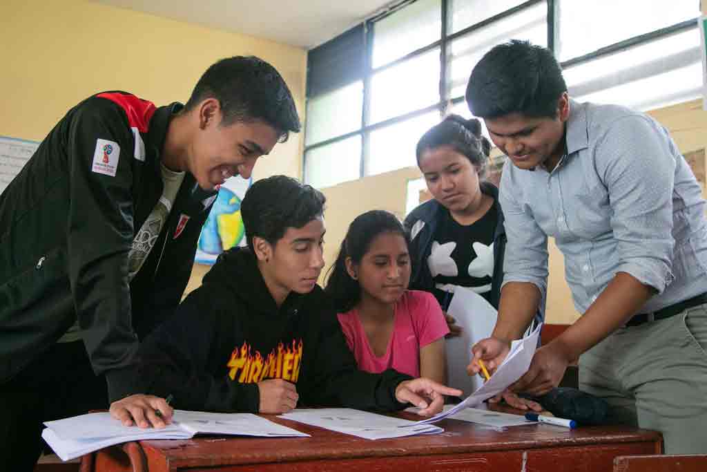 Jóvenes explican clases a alumnos de colegio.