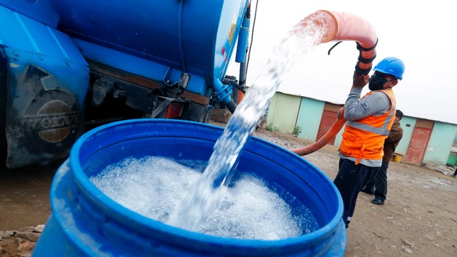 Trabajador llena recipiente con agua potable proveniente de camión cisterna