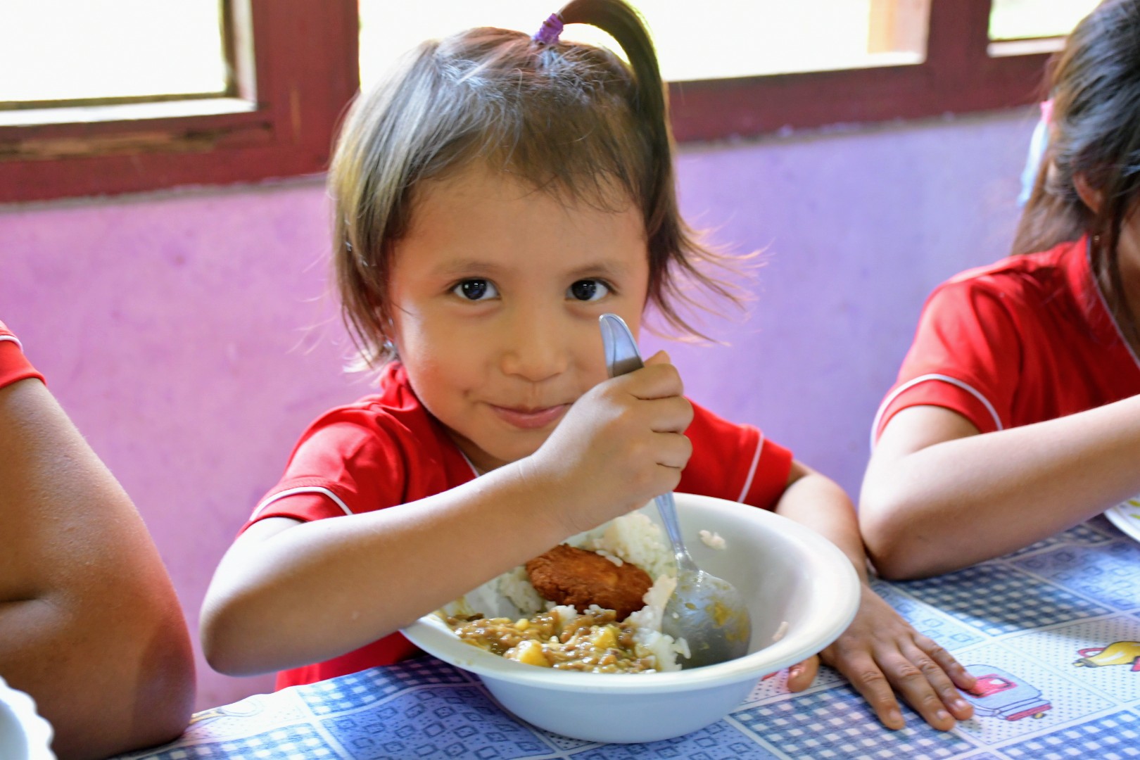 Niña de la aldea infantil consume arroz fortificado y pache en almuerzo nutritivo.