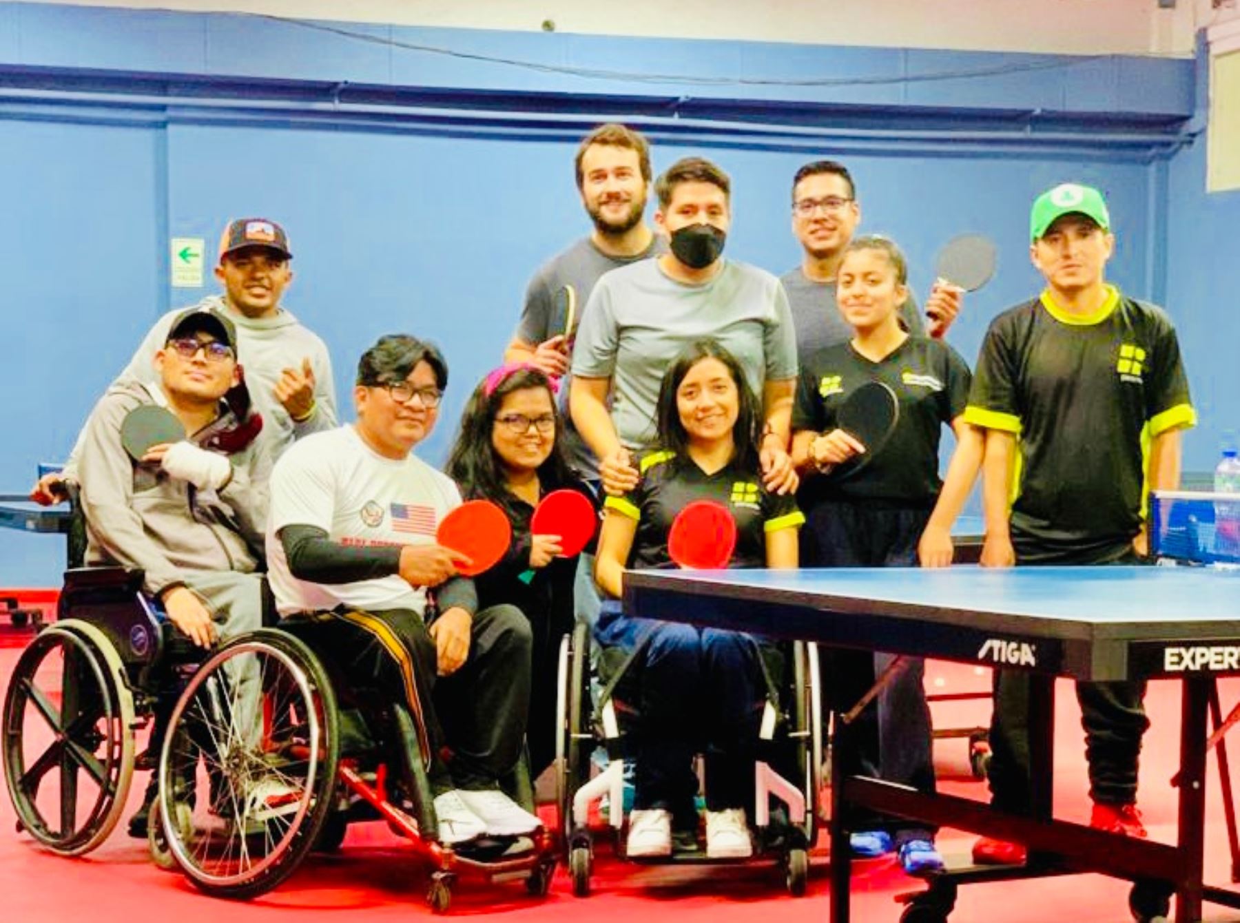 Grupo de niños y niñas con sillas de ruedas posan con sus raquetas de tenis de mesa