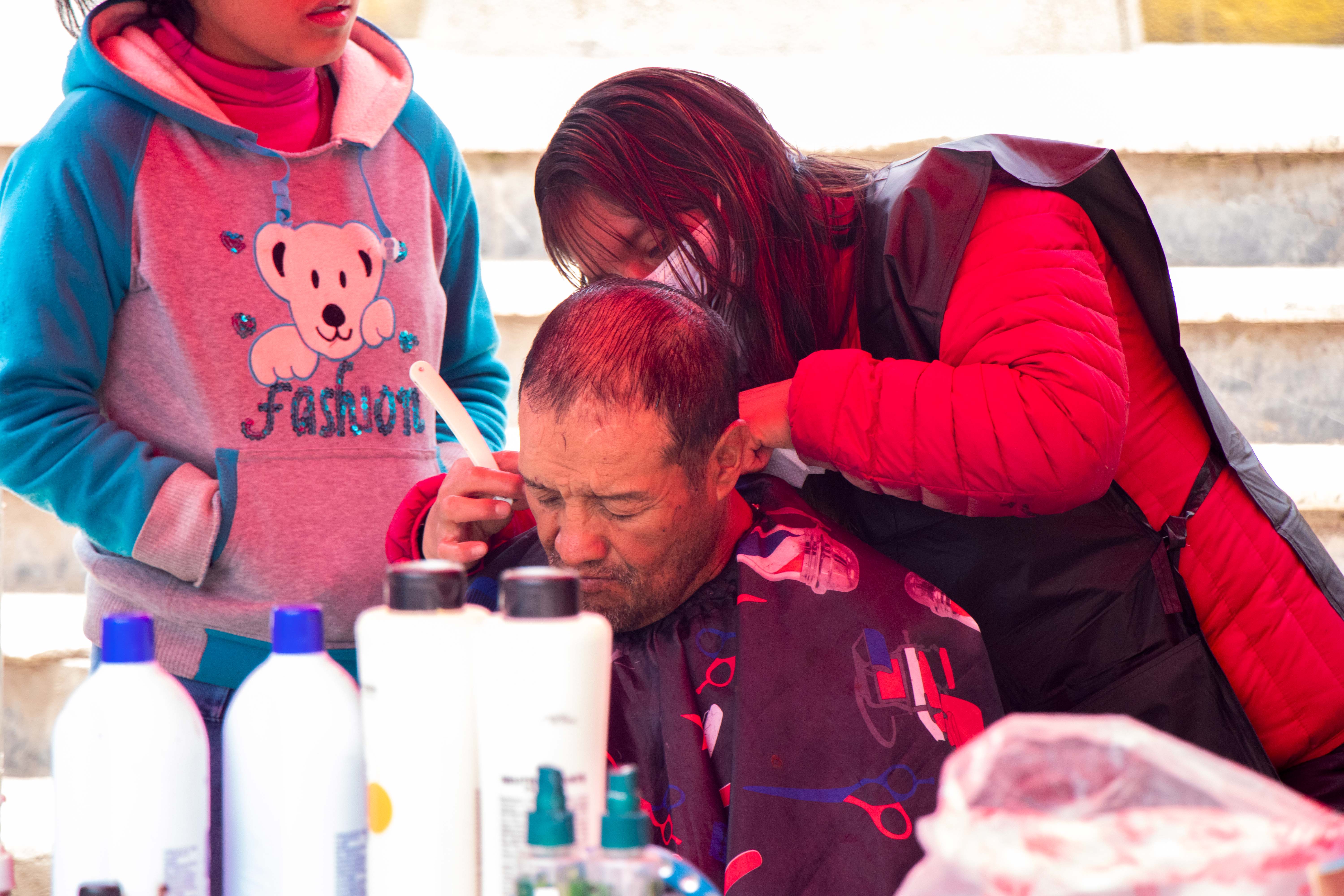 Participantes del taller de cosmetología realizando cortes y tintes gratuitos a los asistentes. Foto 1