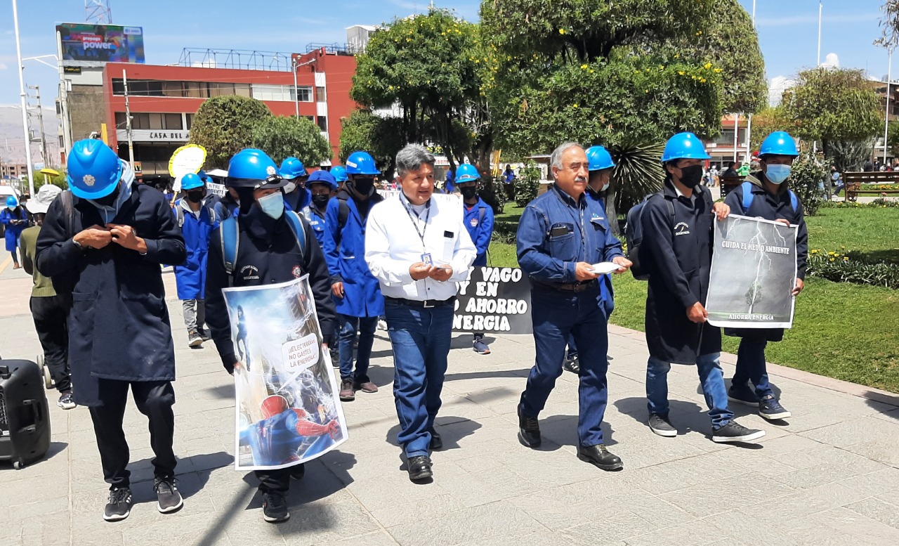 En la imagen hay 6 personas caminando en el parque con los letreros del día del ahorro de energía