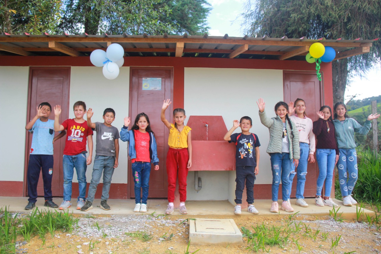 Niños de comunidad posan para la foto delante de una UBS