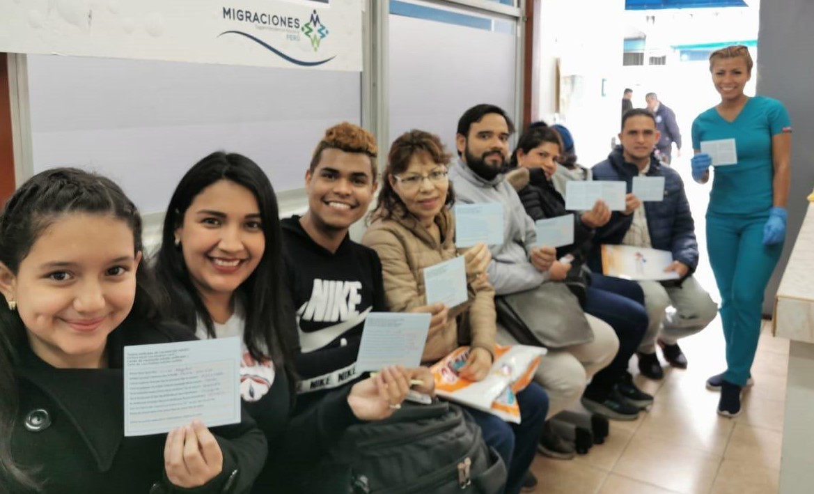 En la foto se ve personas de distintos países en migraciones mostrando la tarjeta unificada de vacunación.