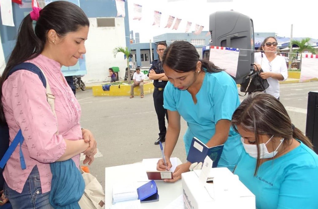 En la foto se ve a enfermeras entregando la tarjeta unificada de vacunación