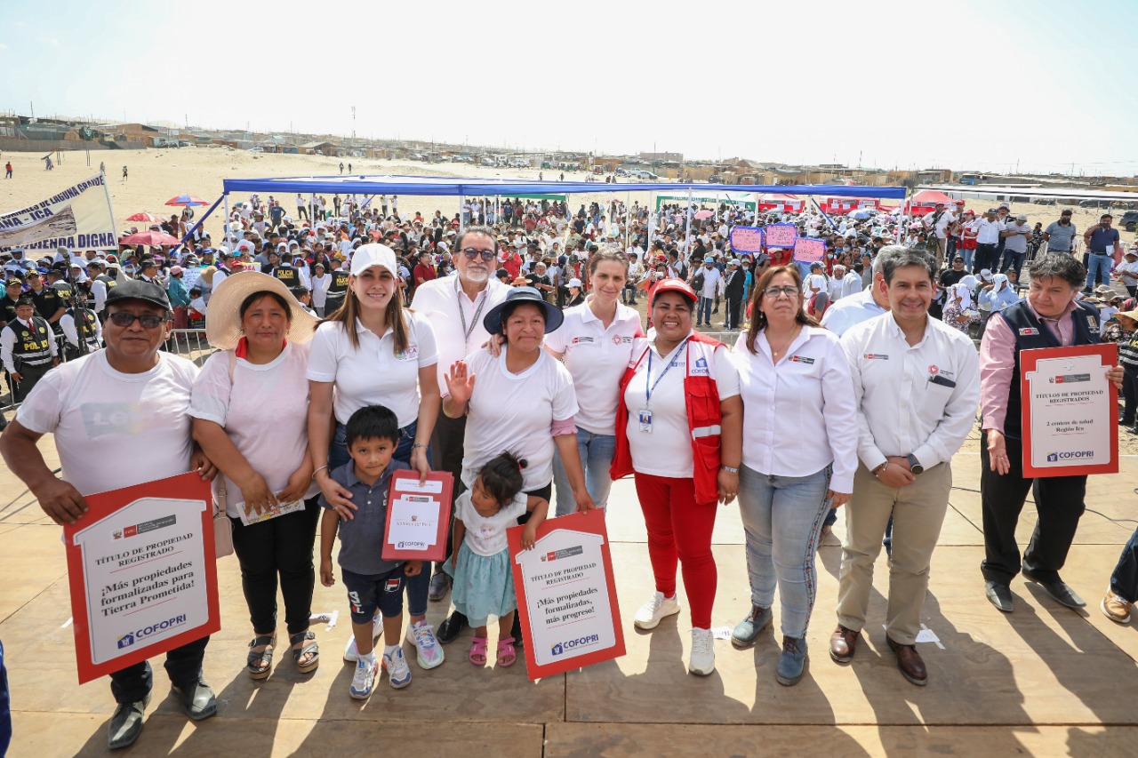 Autoridades posan junto a beneficiarios con sus títulos de propiedad.