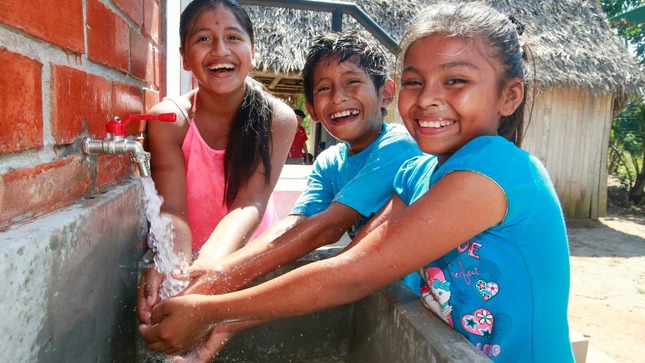 Niños usando el servicio de agua con sistema de captación de agua de lluvias en una UBS