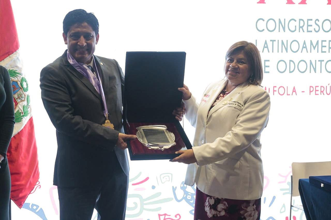 La Ministra de Salud muestra una placa de reconocimiento que le entregó el Colegio de Odontólogos.