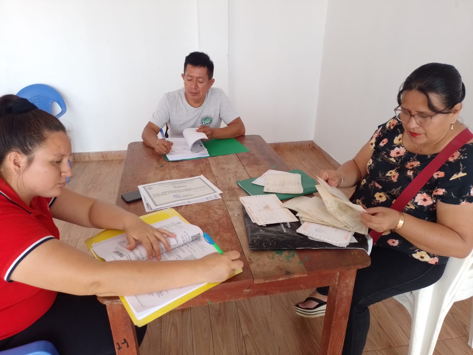 Docentes foliando y firmando documentos que presentarán.