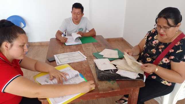 Docentes foliando y firmando documentos que presentarán.