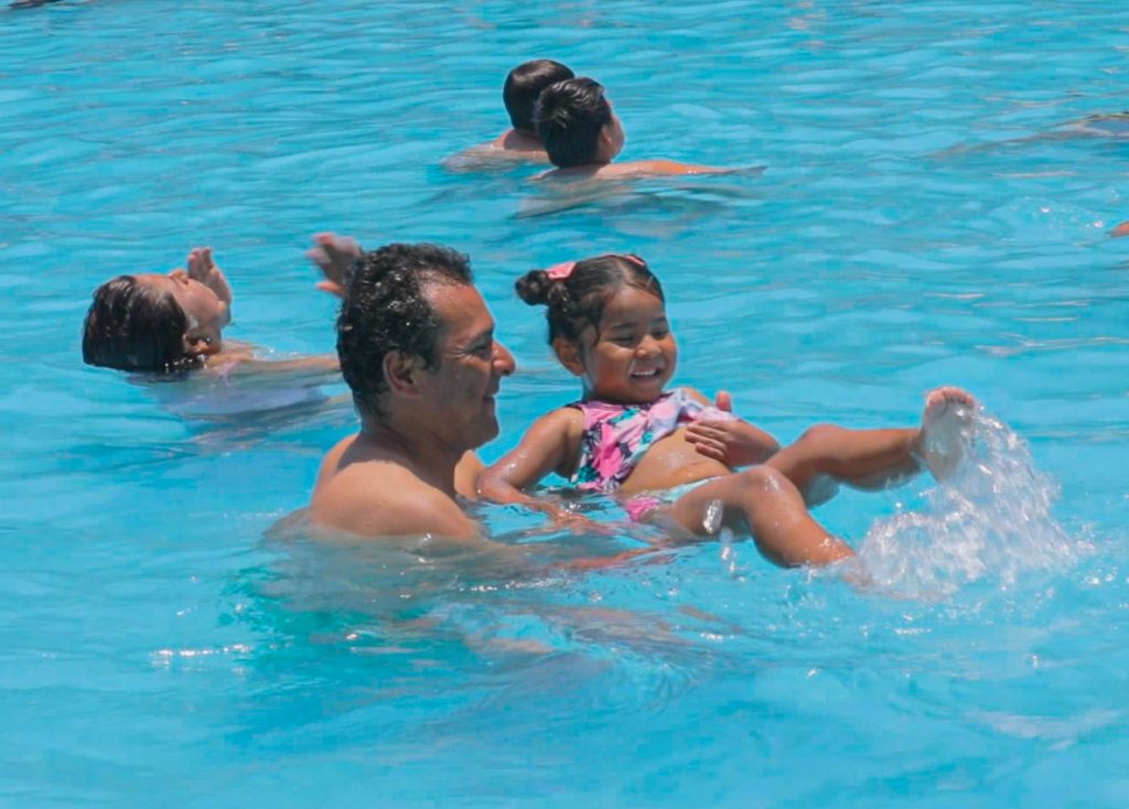Niña jugando con papá en la piscina