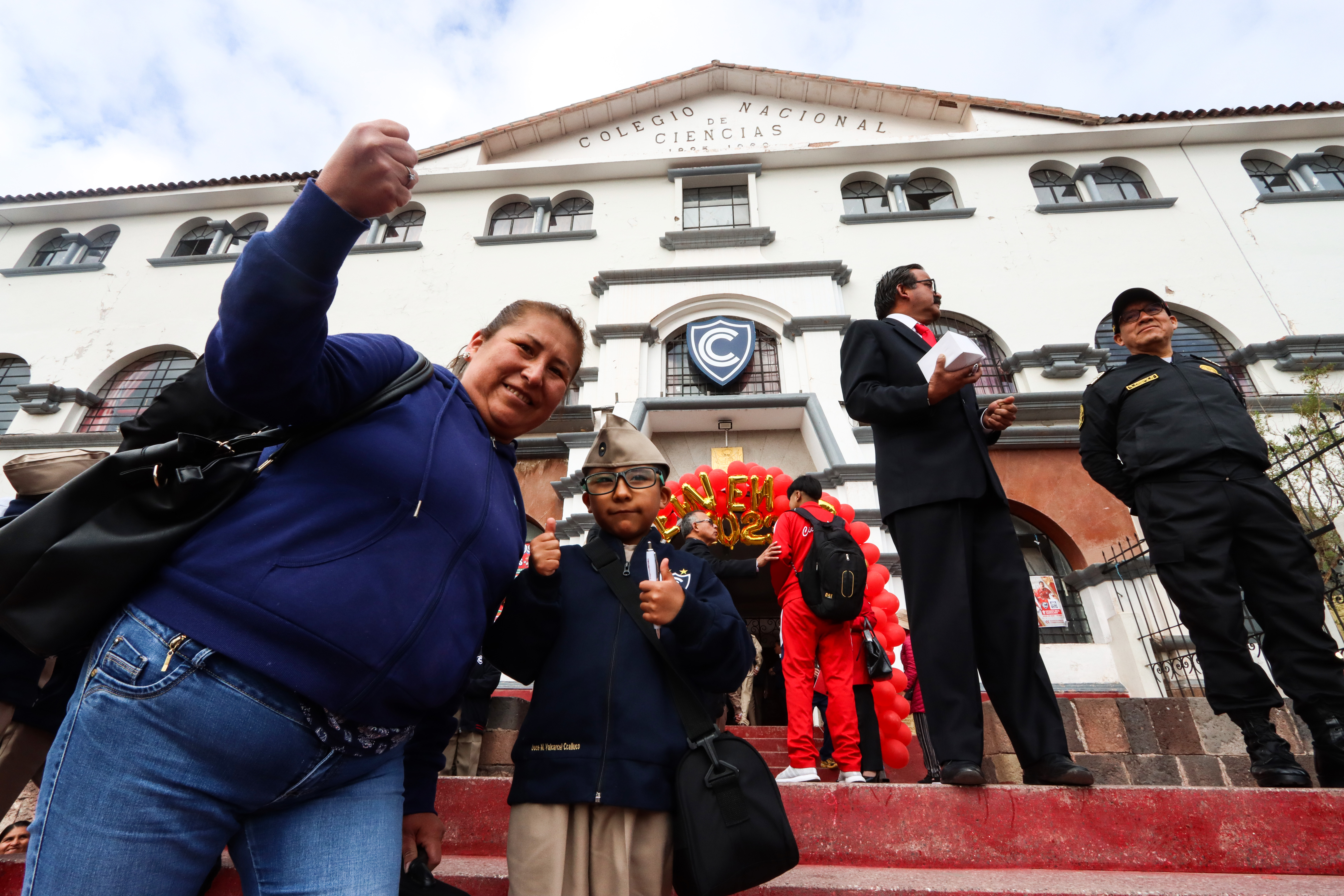 Madre posa junto a su hijo, ambos alegres, en su primer día de clases.
