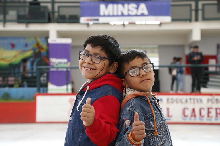 Imagen. Dos niños beneficiarios muestran sonrientes los lentes recibidos