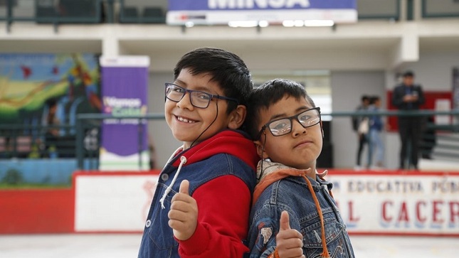 Imagen. Dos niños beneficiarios muestran sonrientes los lentes recibidos