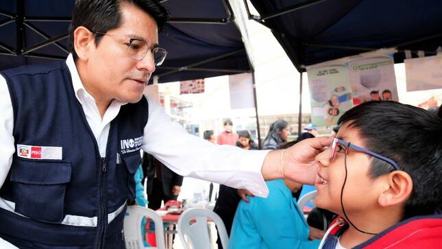 Imagen. Personal del INO prueba como le quedan a un niño beneficiario sus lentes nuevos 