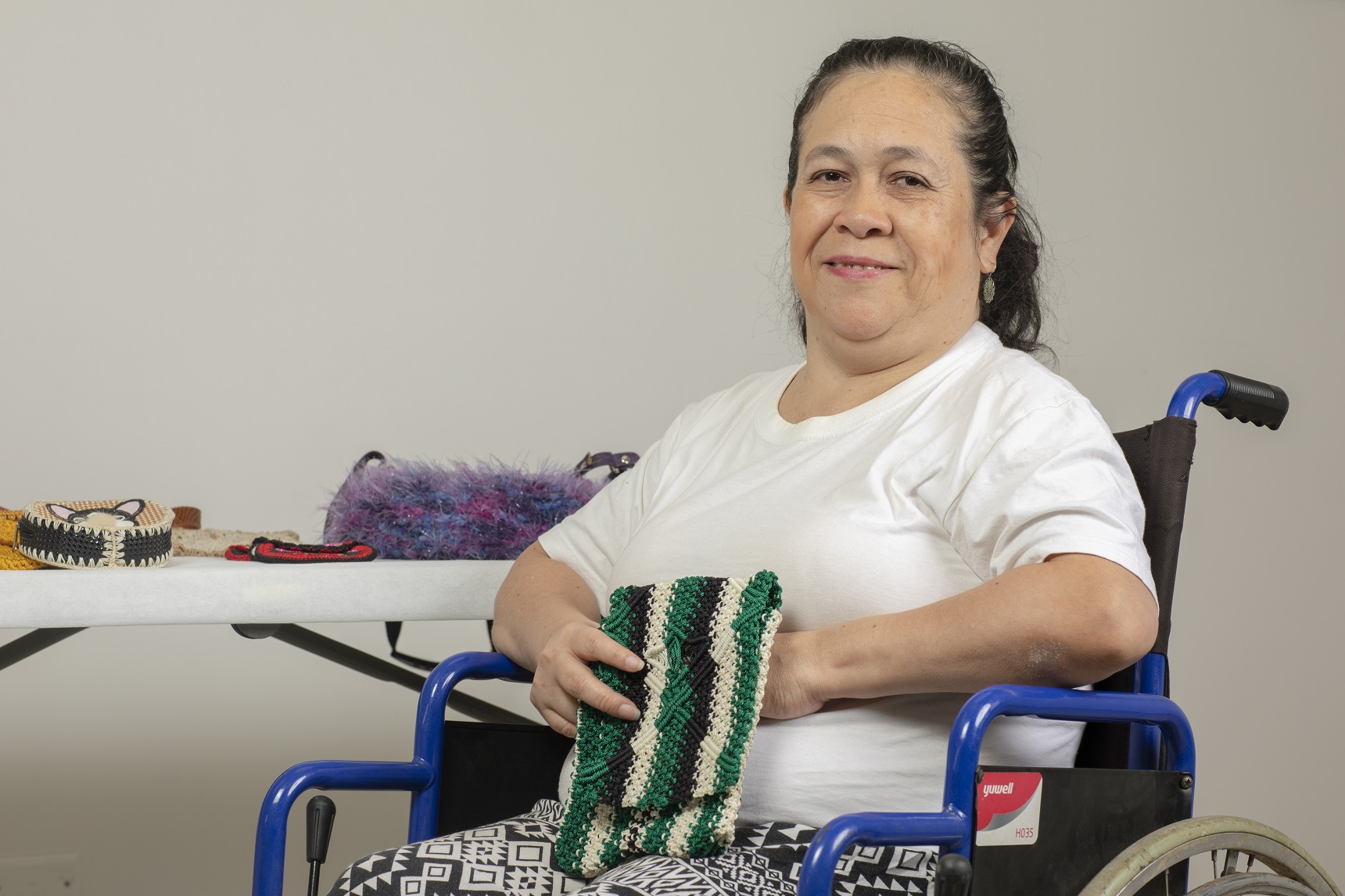 Mujer con discapacidad en silla de ruedas muestras sus tejidos .
