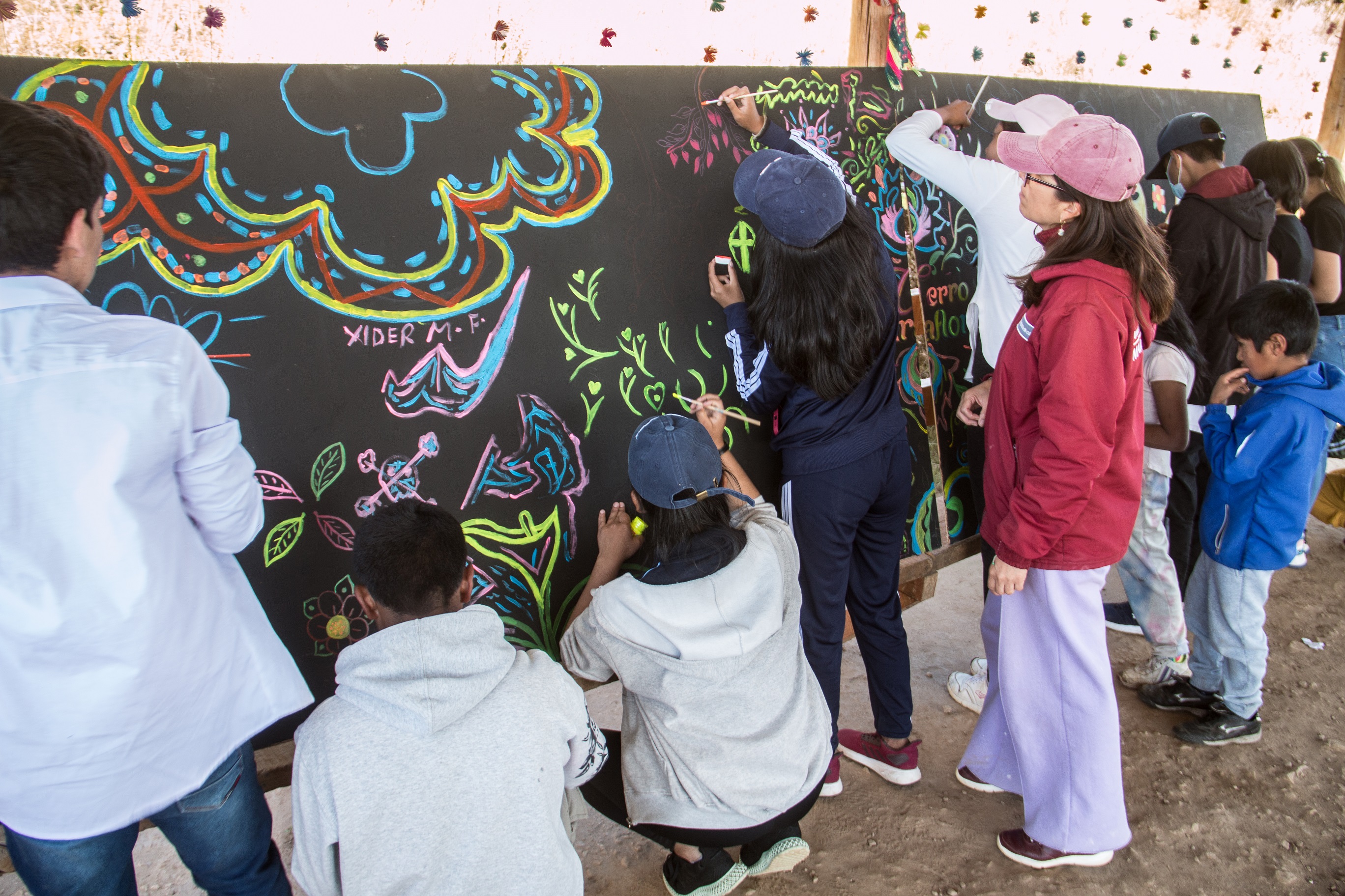 Líderes scolares participando del pintado de un mural como parte de la actividad cultural