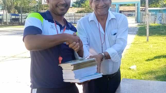 Autor de libros entregando algunos ejemplares a docente de I.E. beneficiada.