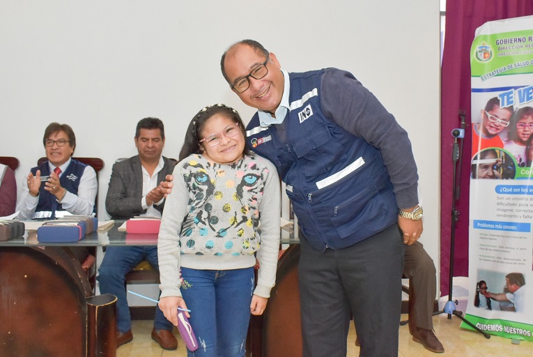 Niña beneficiada posa sonriente con profesional del INO