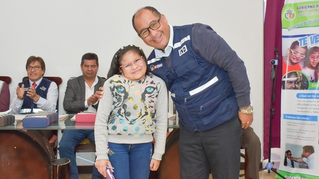 Niña beneficiada posa sonriente con profesional del INO