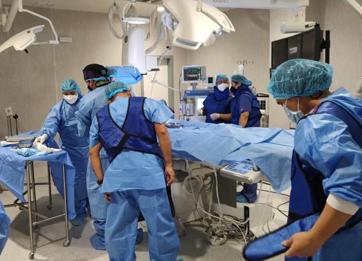 Médicos de la Dirección de Sanidad Policial (Dirsapol) y del Instituto Nacional Cardiovascular “Carlos Alberto Peschiera Carrillo” de EsSalud realizaron con éxito la primera operación de cardiología intervencionista en el Hospital Nacional de la Policía Nacional del Perú "Luis N. Sáenz", ubicado en el distrito de Jesús María.
El procedimiento médico de alta complejidad, denominado cateterismo percutáneo, fue aplicado a una paciente menor de edad de Piura, quien fue diagnosticada con una enfermedad congénita de Conducto Arterioso Persistente.
La operación forma parte de los nuevos servicios que brindará dicho nosocomio a toda la familia policial, gracias a la adquisición de un moderno cineangiógrafo, que es un dispositivo utilizado en el diagnóstico y manejo de las lesiones vasculares cerebrales y permite obtener imágenes digitales multidimensionales en alta calidad en tiempo real.
La incorporación de estas nuevas especialidades médicas obedece a las disposiciones del ministro del Interior, Vicente Romero, y del comando institucional de la Policía Nacional, para optimizar la atención de pacientes y reducir el número de casos que son derivados a otras clínicas o centros de salud.
En la presentación de los resultados de esta intervención médica participaron el titular del sector Interior, Vicente Romero y el comandante general de la PNP, General de Policía Jorge Angulo. También estuvieron presentes el director del Hospital Nacional PNP, Gral. Médico SPNP Moisés Rojas, y el director del Instituto Nacional Cardiovascular de EsSalud, Frank Britto.
El ministro Vicente Romero señaló que el inicio de este tipo de intervenciones de alta cirugía en el Hospital de Policía marca un hito importante en la calidad de la atención médica ofrecida a la familia policial y a la comunidad en general.
“Nos llena de orgullo ver cómo se va concretando este hito significativo para el servicio y la atención de la familia policial. Como autoridad del sector Interior, debo decir que la salud y el bienestar de todos nuestros policías y sus familias tienen alta prioridad para nuestra gestión”, manifestó el ministro.
Indicó que el sector Interior ha suscrito 39 convenios a nivel nacional con gobiernos regionales, institutos especializados, hospitales y centros de salud para que el personal policial y sus derechohabientes puedan recibir una atención adecuada, inmediata y eficiente.