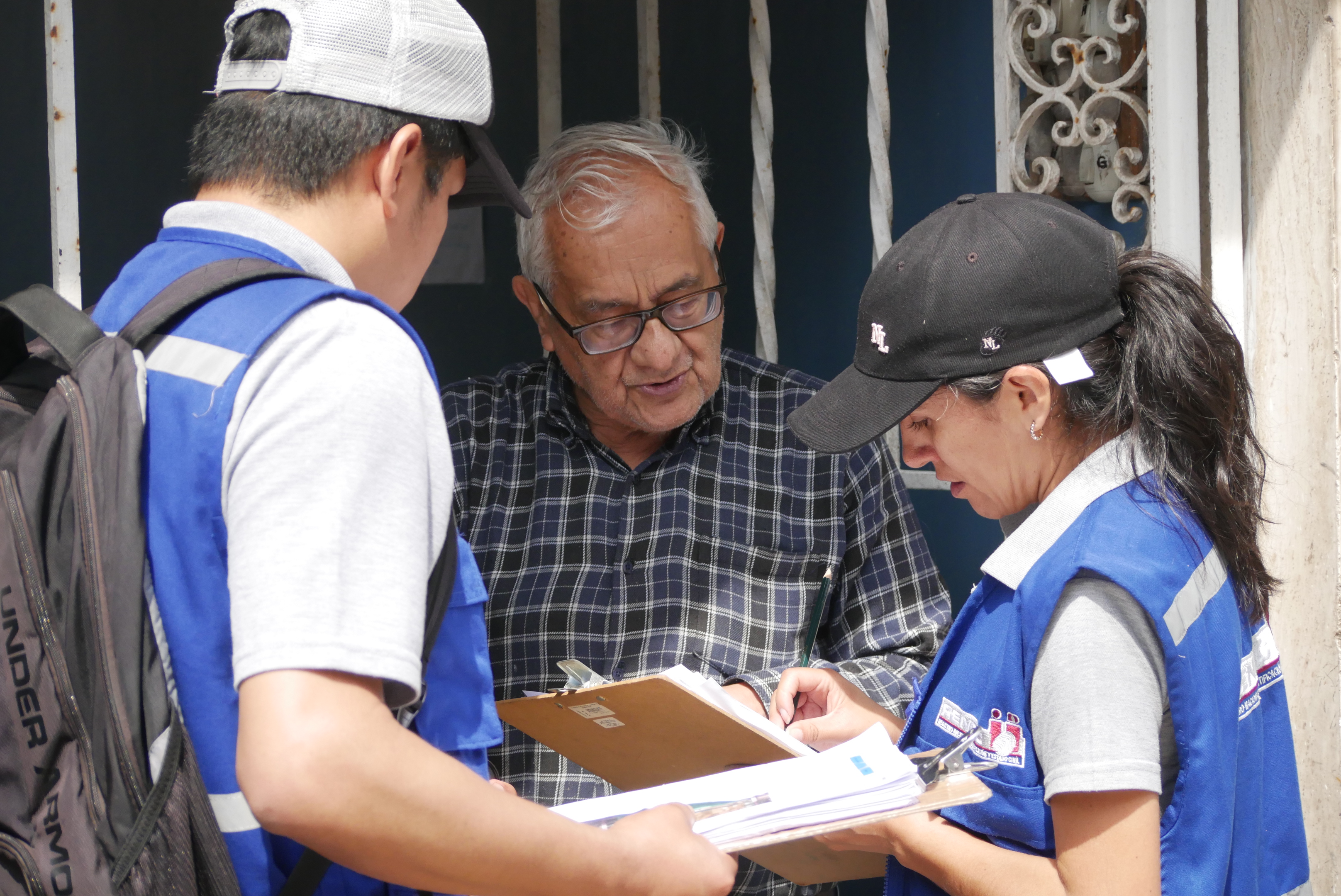 Fiscalizadores de Reniec realizando la verificación de domicilio en el frontis de una casa.