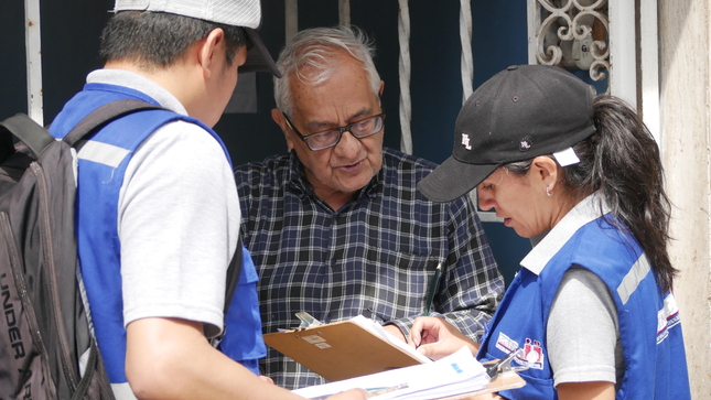 Fiscalizadores de Reniec realizando la verificación de domicilio en el frontis de una casa.