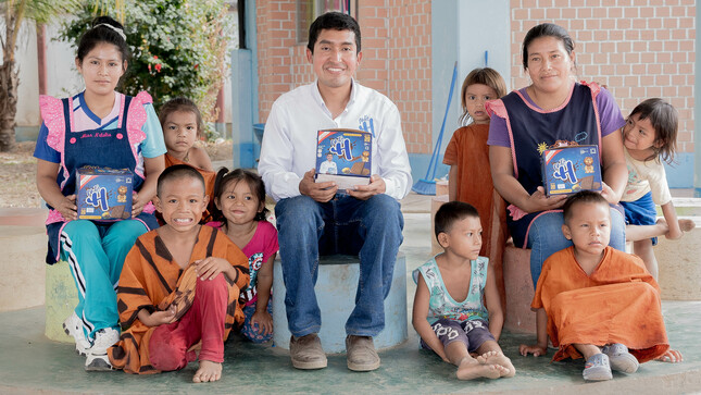 Emprendedor ayacuchano Julio Garay acompañado de madres y niños, mostrándoles la línea Nutri H